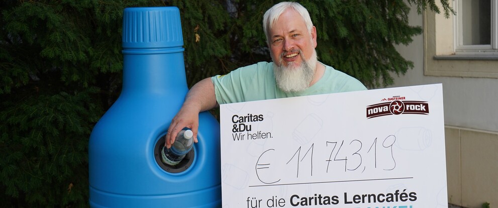 Mann mit Bart wirft Flasche in blaue Sammelbox, hält Scheck über 11.743,19 Euro für Caritas Lerncafés
