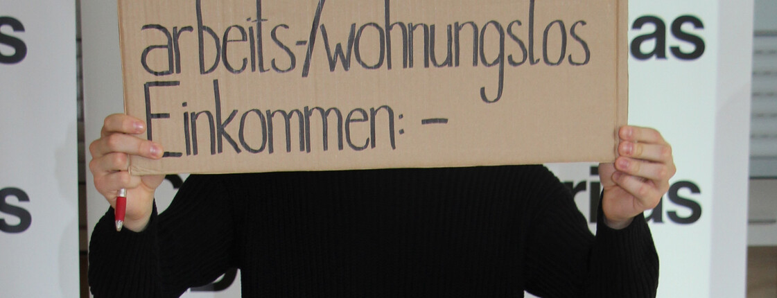 Person hält Pappschild in die Höhe auf dem steht "Franz, 19, arbeits- und wohnungslos!"