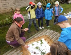 Caritas Pädagogin mit Kindern beim Kräuterinspizieren.