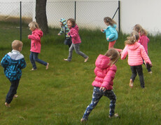 Kinder aus dem Caritas Kindergarten Unterfrauenhaid laufen barfuß im Rasen beim feuchten Tau-Lauf.