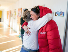 Caritas-Direktorin Melanie Balaskovics umarmt einen Bewohner.