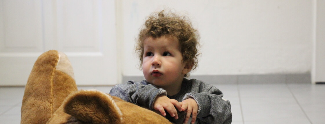 Ein kleiner Bub im Mutter-Kind-Haus spielt mit einem Teddy.