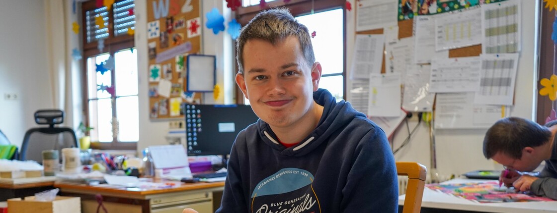 Ein junger Bewohner lächeln beim basteln von Weihnachtsprodukten.