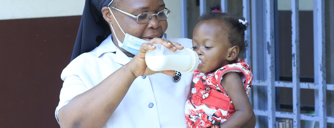 Nonne füttert ein kleines Mädchen mit der Flasche im Waisenhaus N'sele in der DR Kongo.
