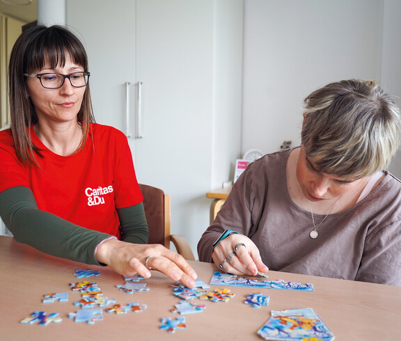 Eine Bewohnerin und eine Betreuerin lösen gemeinsam ein Puzzle.
