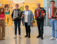 Eine Gruppe von vier Musikern mit Akkordeons und Klarinette, zusammen mit einer weiteren Person in der Mitte. 
