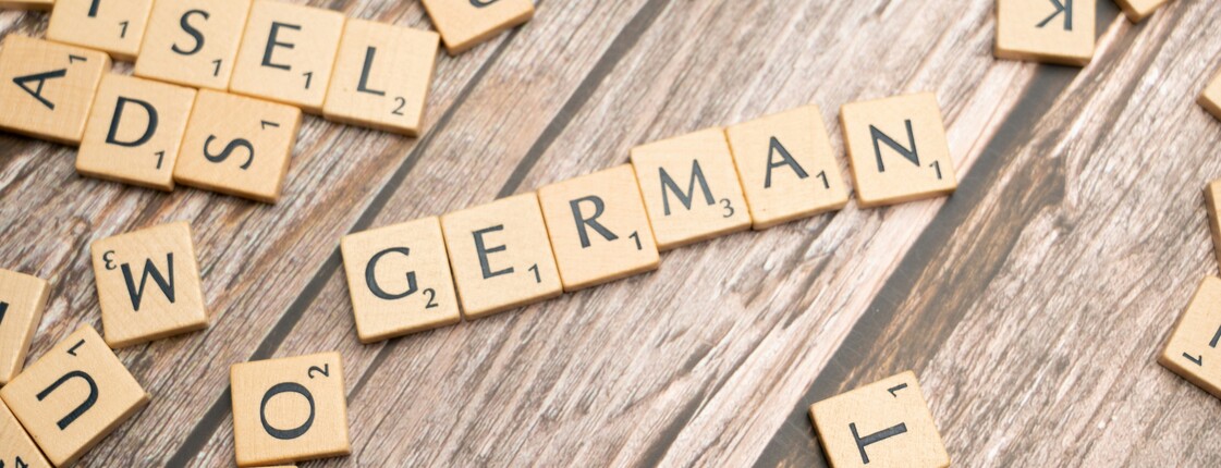 Mit Scrabble Buchstaben wurde auf einem Holztisch das Wort "GERMAN" gelegt.