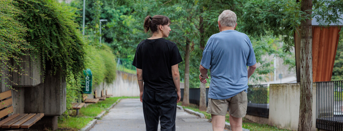 Eine junge Frau und ein Senior gehen gemeinsam spazieren.