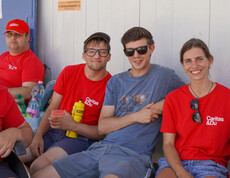 Bewohner und Betreuer*innen sitzen mit Caritas T-Shirts draußen im Schatten.