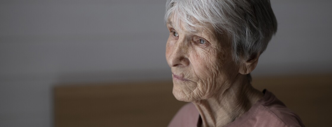 Eine Pensionistin blickt nachdenklich zur Seite.