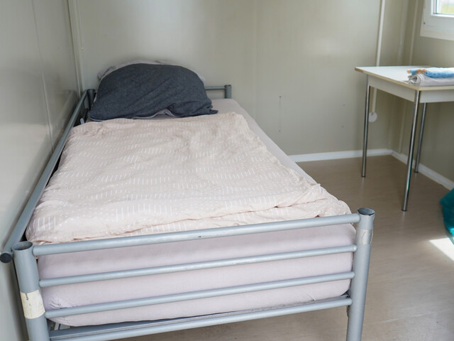 Innenbereich des Containers mit einem Einzelbett und einem kleinen Tisch.