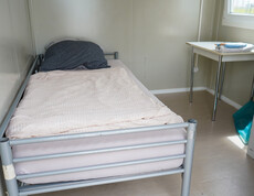 Innenbereich des Containers mit einem Einzelbett und einem kleinen Tisch.