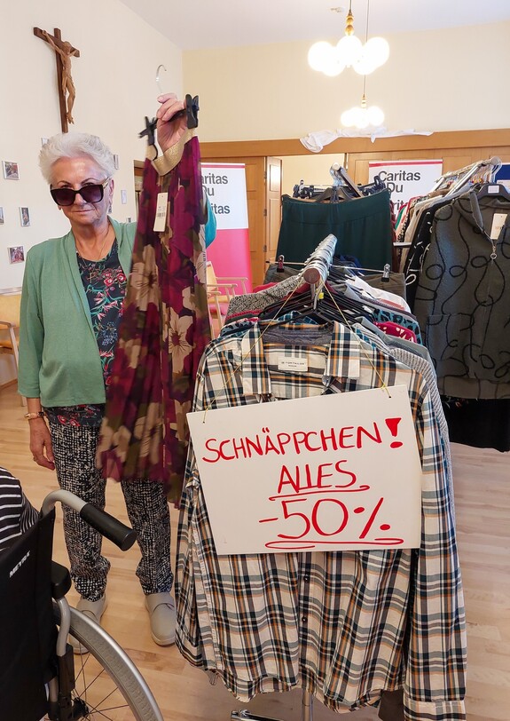 Ein Kleiderständer mit Hemden und Blusen ist beschriftet mit "-50% auf alles".