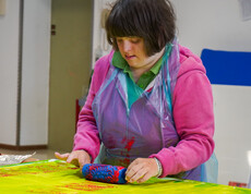 Eine Frau malt mithilfe einer Farbrolle auf einer gelben Leinwand.