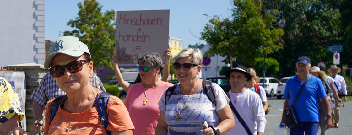 Mitglieder der PfarrCaritas gehen durch den Ortskern in Pinkafeld und halten dabei Schilder gegen Hunger in der Welt in die Luft.