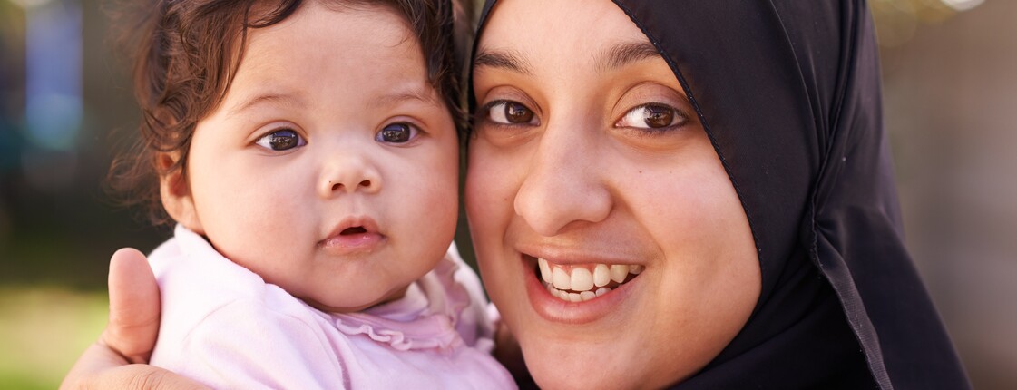 Eine Frau mit Kopftuch hält ein Baby.