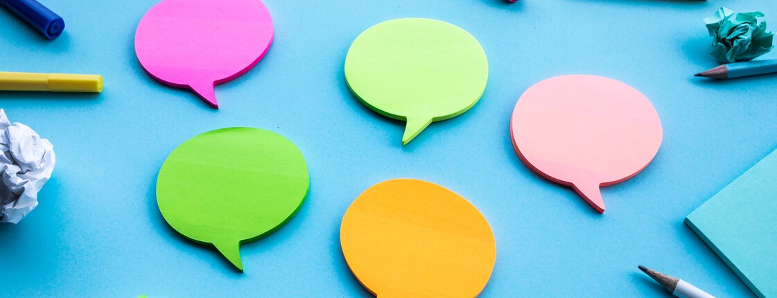 Verschiedene bunte Sprechblasen vor einem blauen Hintergrund.