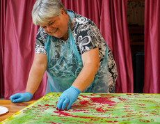 Eine Frau malt lächelnd ein Bild.