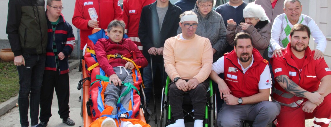 Caritas MitarbeiterInnen mit den BewohnerInnen vom Caritas Haus St. Stephan und den Kursleitern vom Roten Kreuz Burgenland vor dem Rettungswagen.