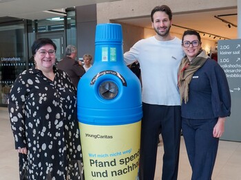 Caritas Burgenland Direktorin Melanie Balaskovics und zwei Mitarbeiter*innen stehen neben einem Pfandaufsteller.