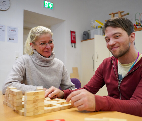 Ein Bewohner und eine Frau lächeln und spielen mit Bausteinen.
