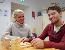 Ein Bewohner und eine Frau lächeln und spielen mit Bausteinen.