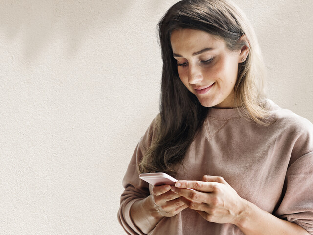 Frau schaut lächelnd auf ihr Handy