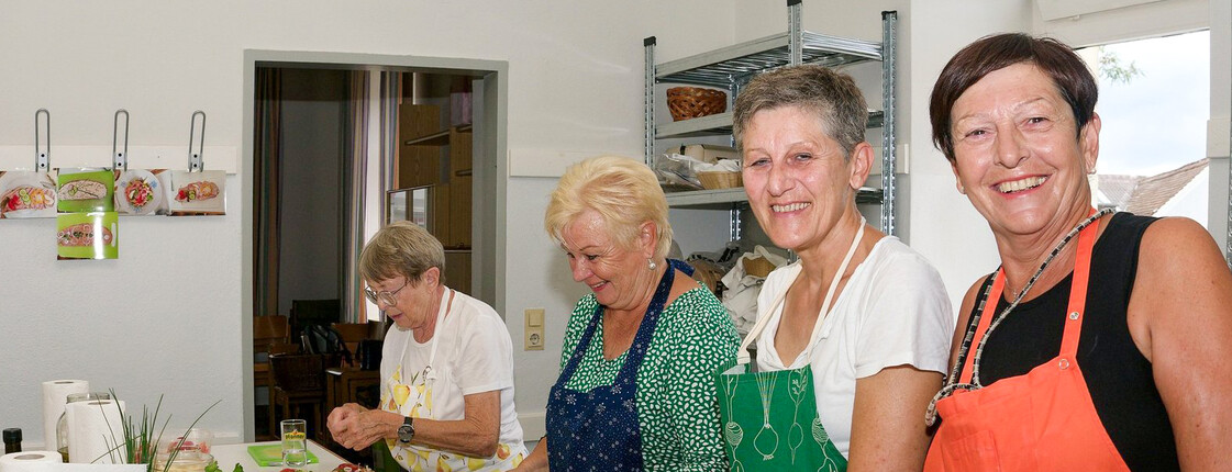 Vier Frauen stehen in der Küche und bereiten Speisen für eine Aktion vor.