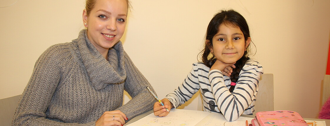 Freiwillige Helferin lernt mit einem Kind im Caritas Lerncafé.