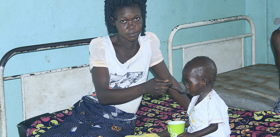 Mutter füttert ihr Kind im Caritas Ernährungszentrum in Kinshasa, DR Kongo