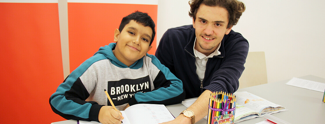 Ein Freiwilliger und ein Kind im Caritas Lerncafé beim Lernen