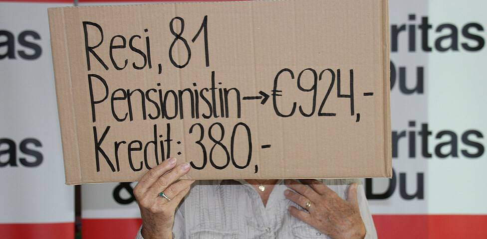 Person hält Pappschild in die Höhe auf dem steht "Resi, 81, Mindestpensionistin"