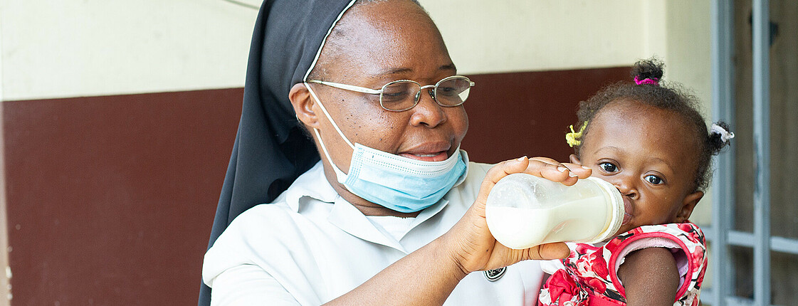 Eine Schwester füttert ein Baby im Caritas Ernährungszentrum N'sele