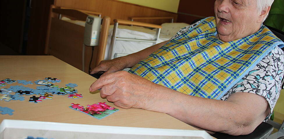 Eine Bewohnerin spielt Puzzle im Caritas Haus Lisa