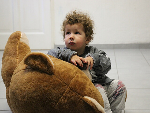 Ein kleiner Bub im Mutter-Kind-Haus spielt mit einem Teddy.