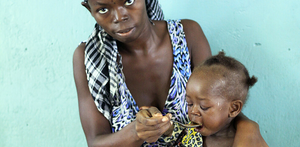 Mutter im Kongo füttert ihr unterernährtes Kind