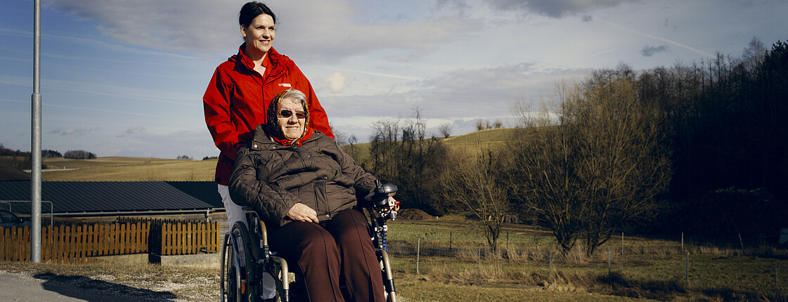 Seionrin im Rollstuhl mit Caritas Pflegerin